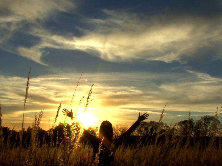 A person with raised hands in a field.